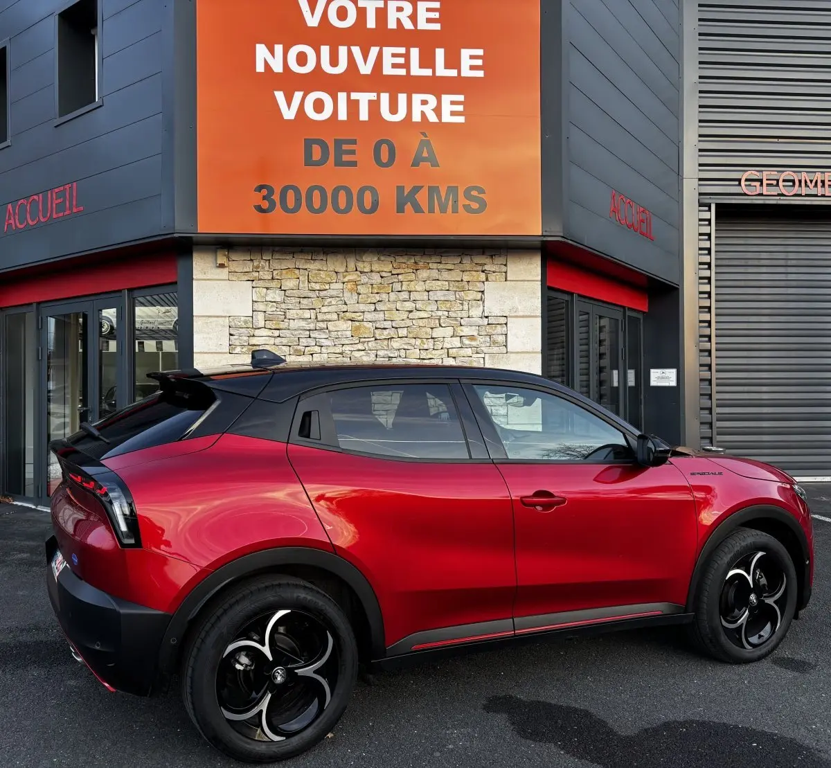 Vue de profil droit d'une Alfa Romeo Junior rouge 2024 avec toit noir et jantes noires distinctives.