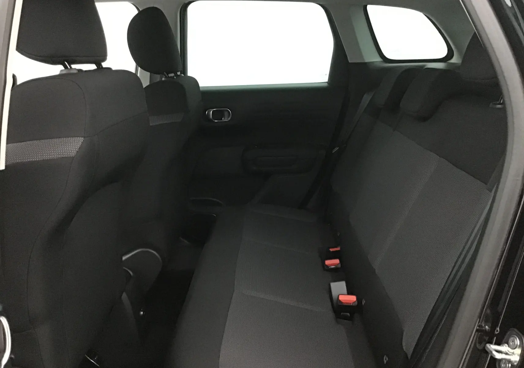 Vue intérieure côté droit de la banquette arrière noire du Citroën C3 Aircross 2024 avec appuie-têtes et ceintures visibles.