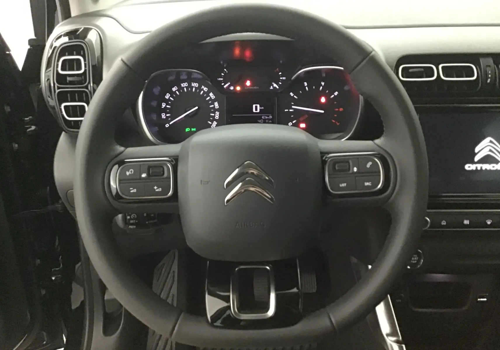 Vue rapprochée du volant noir de la Citroën C3 Aircross 2024 avec tableau de bord et écran tactile allumé.