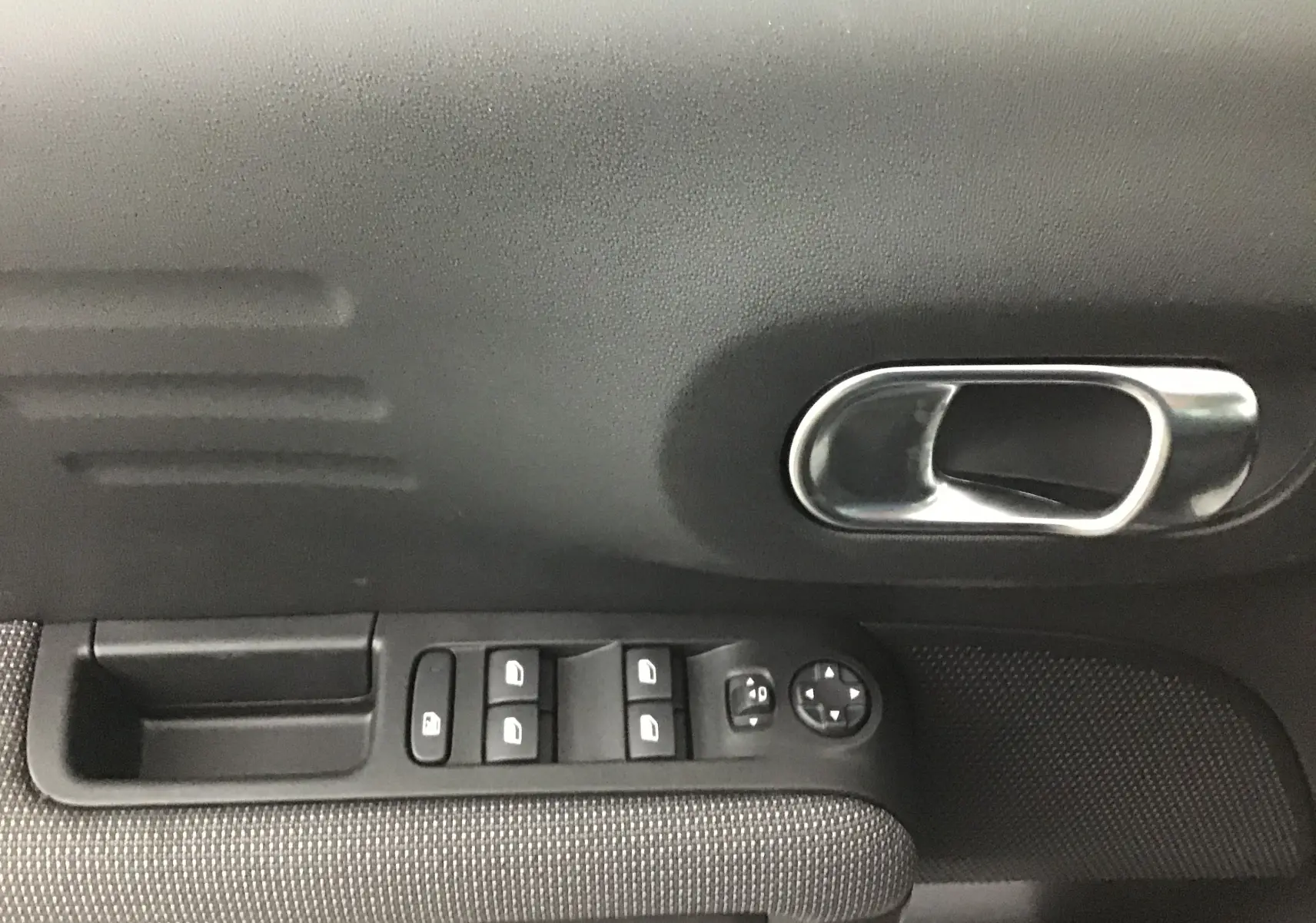 Poignée intérieure côté gauche avec commandes des vitres et rétroviseurs du Citroën C3 Aircross noir 2024.