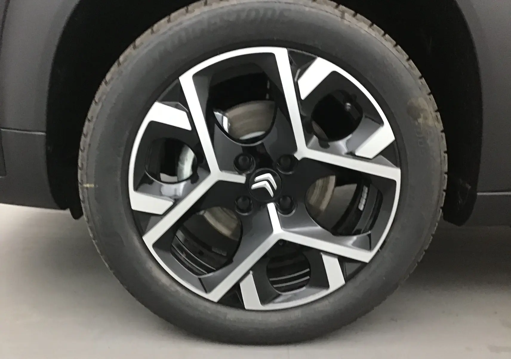 Gros plan sur la jante noire et argentée de la roue avant gauche du Citroën C3 Aircross 2024 noir.