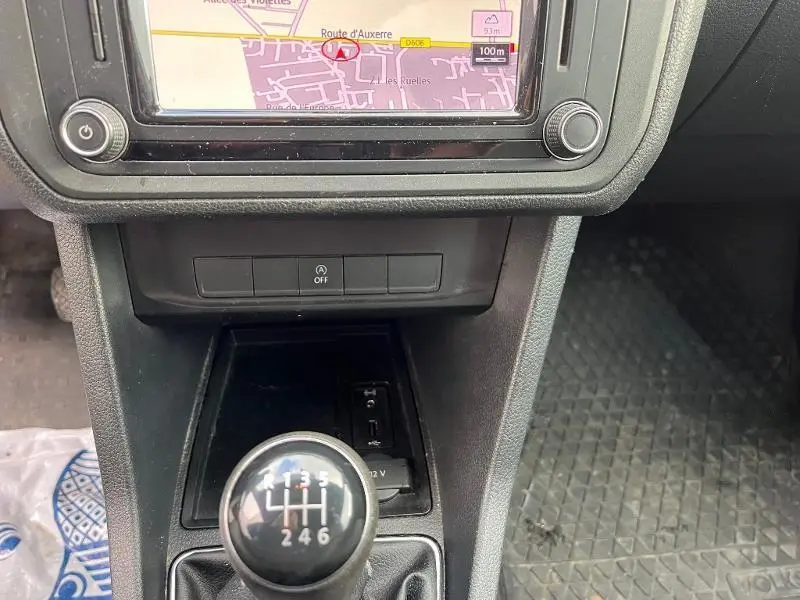 Gros plan sur la console centrale noire du Volkswagen Caddy Van blanc, avec levier de vitesses manuel 6 rapports et écran tactile GPS.