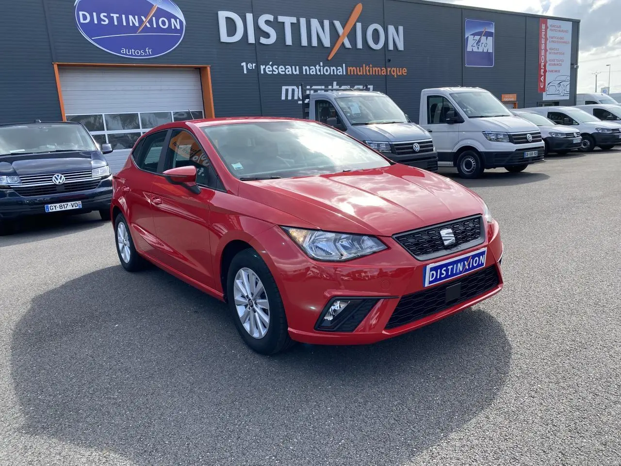 SEAT Ibiza rouge pur vue 3/4 avant droit sur parking avec calandre noire et jantes alliage 15 pouces.