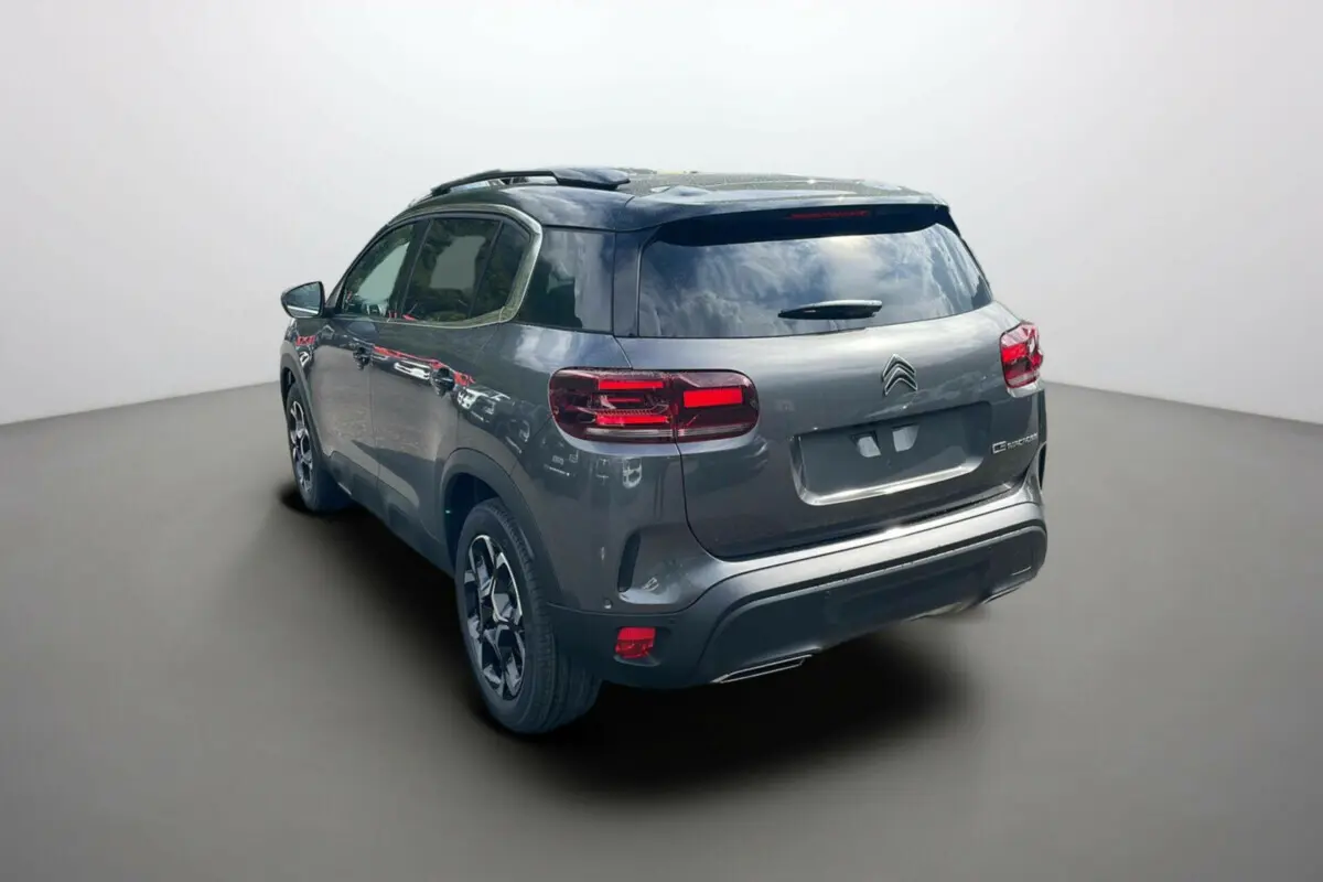 Vue 3/4 arrière gauche du Citroën C5 Aircross 2025 gris platinium avec toit noir et feux arrière LED distinctifs.