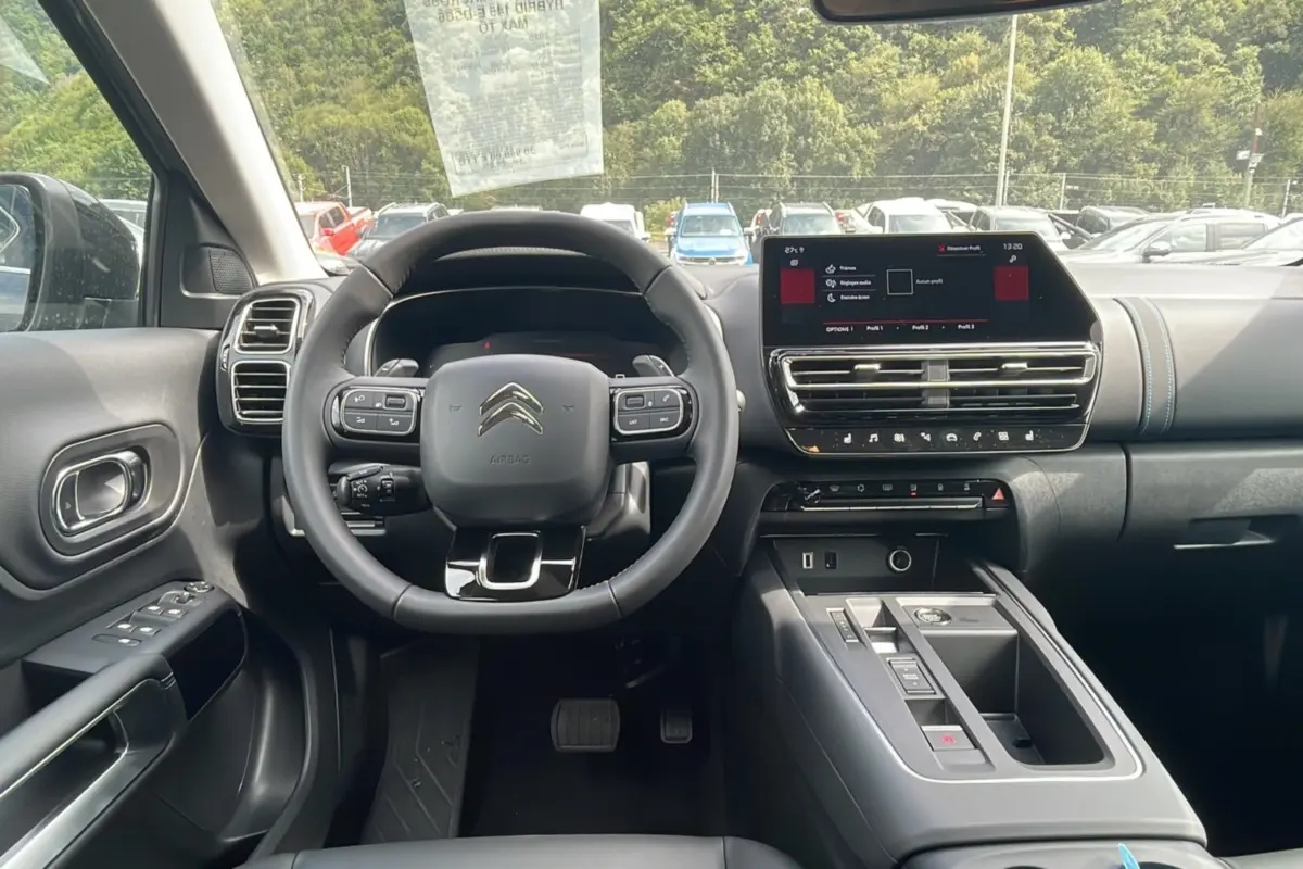 Intérieur moderne du Citroën C5 Aircross Hybrid 2025, vue frontale du tableau de bord avec écran tactile et volant multifonction.