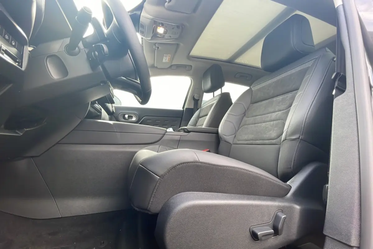 Intérieur du Citroën C5 Aircross Hybrid 2025 vu côté conducteur, sièges cuir noir et toit panoramique.