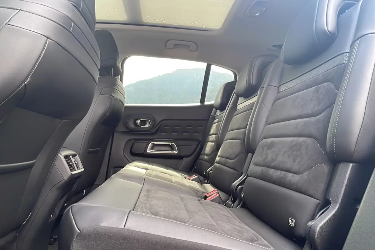 Vue latérale des sièges arrière en cuir noir du Citroën C5 Aircross Hybrid 2025, avec toit panoramique visible.