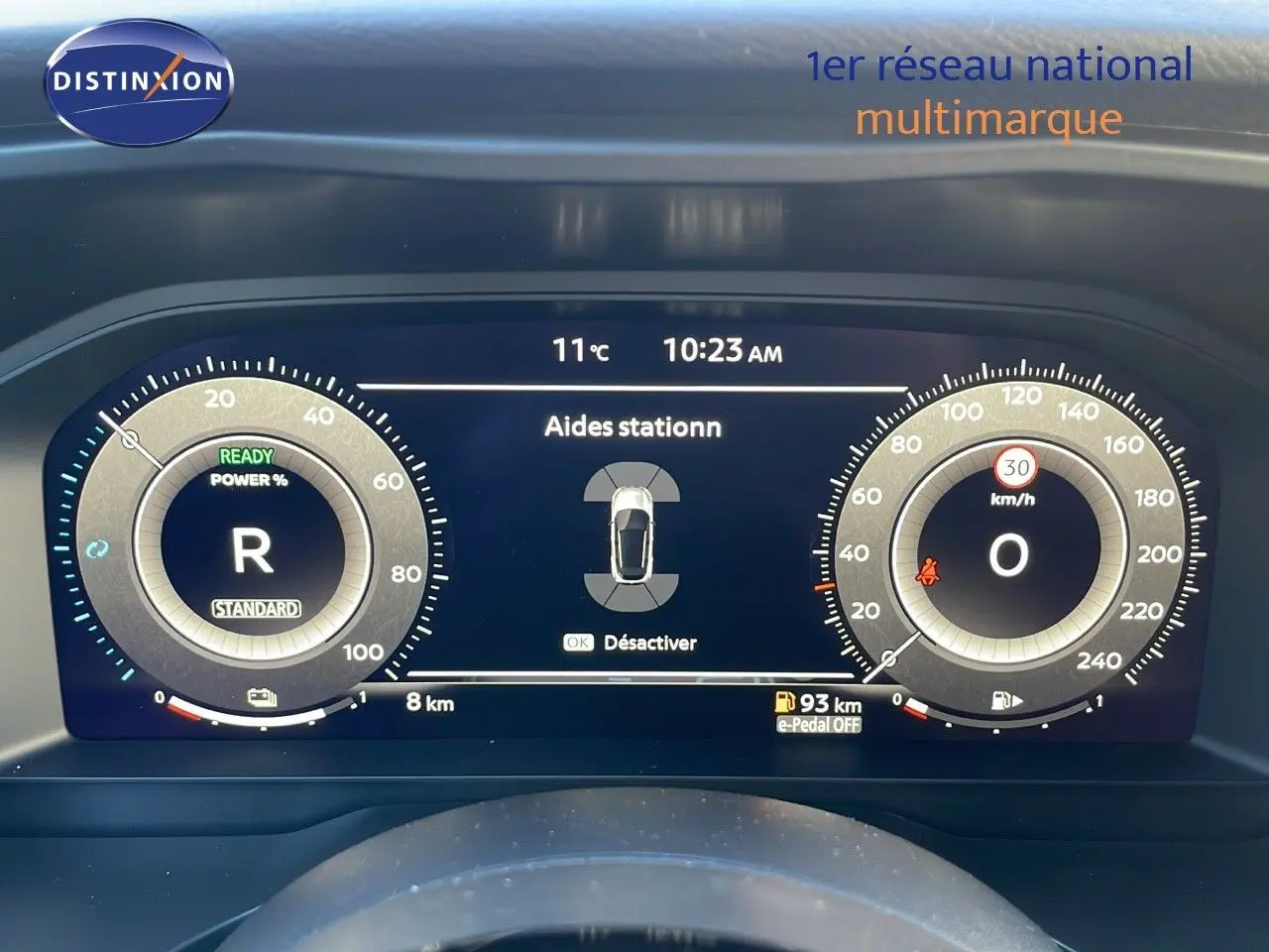 Tableau de bord numérique du Nissan Qashqai 2025 blanc nacré, affichant aides au stationnement et vitesse à 0 km/h.