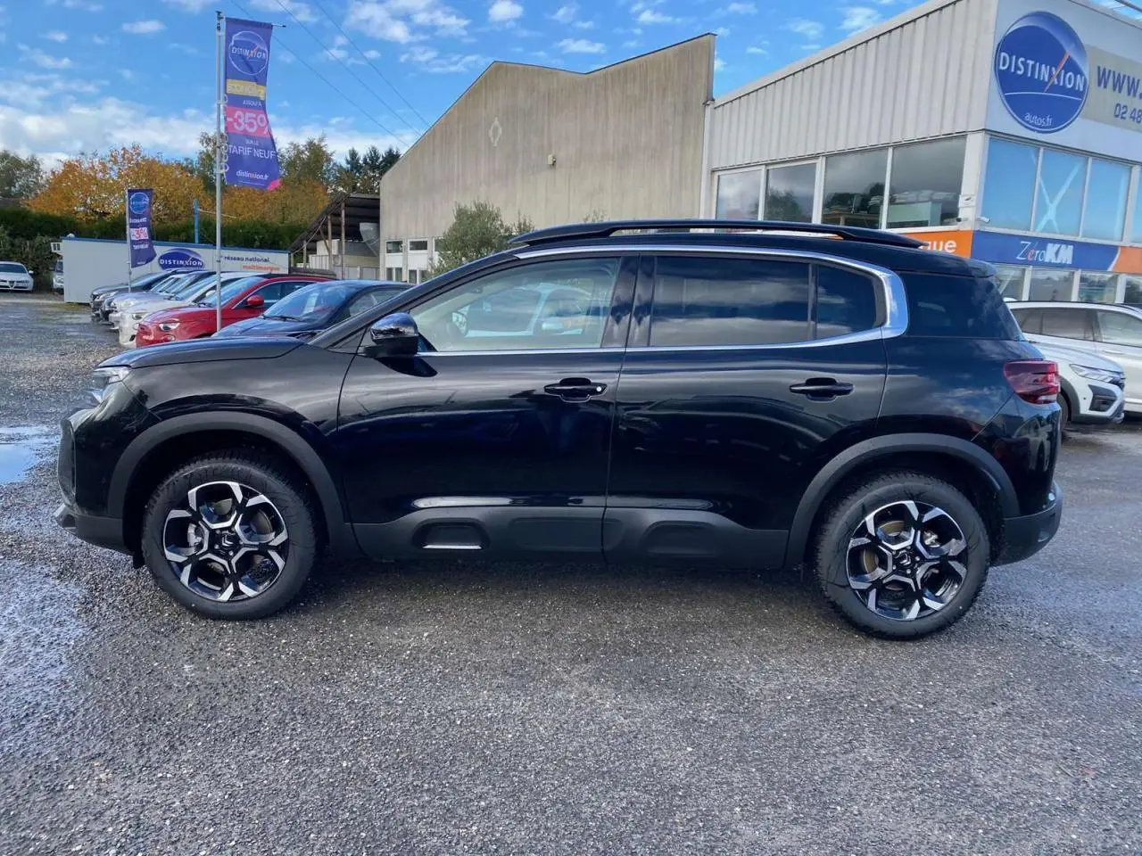 Profil côté gauche du Citroën C5 Aircross noir Perla avec jantes alliage 18'' bi-ton et barres de toit visibles.