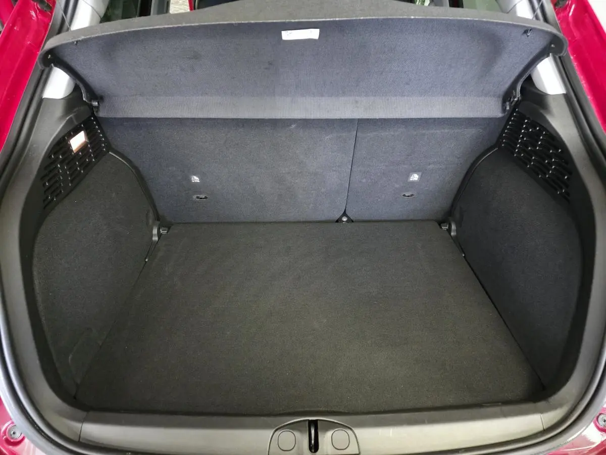 Coffre ouvert vu de dessus d'une Fiat 500X rouge, montrant un espace de rangement propre et bien fini.