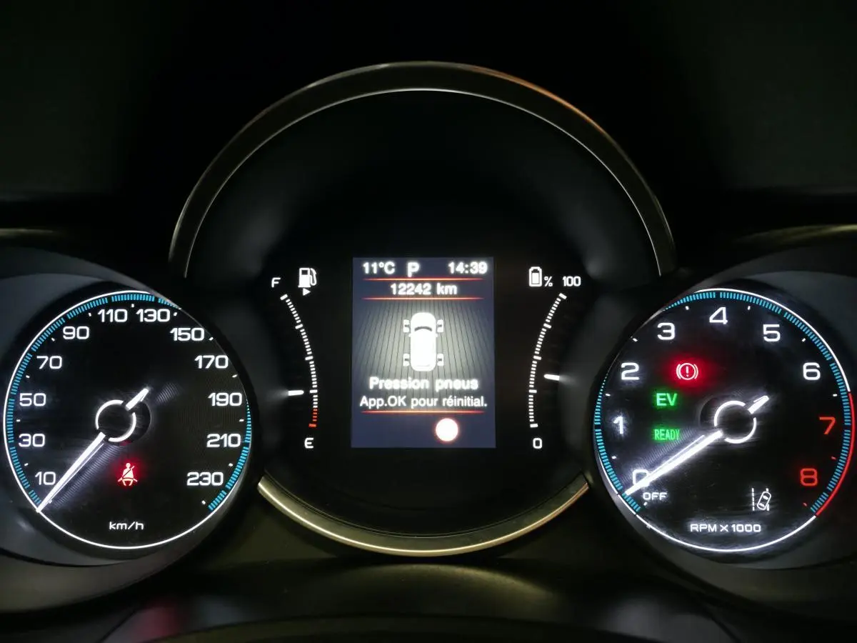 Tableau de bord de Fiat 500X rouge 2024 montrant l'affichage de pression pneus et compteurs vitesse et tours moteur.