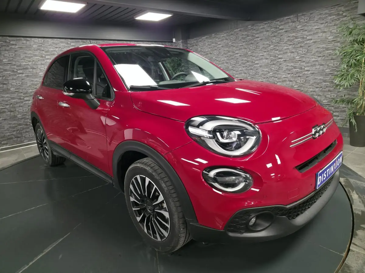 Fiat 500X rouge vue 3/4 avant droit, avec jantes alliage noires et coques de rétroviseurs noires.