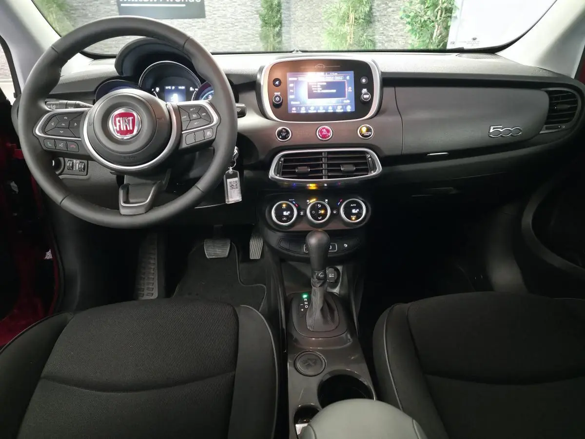 Vue intérieure frontale de la Fiat 500X 2024 avec tableau de bord gris titane et volant multifonction noir.