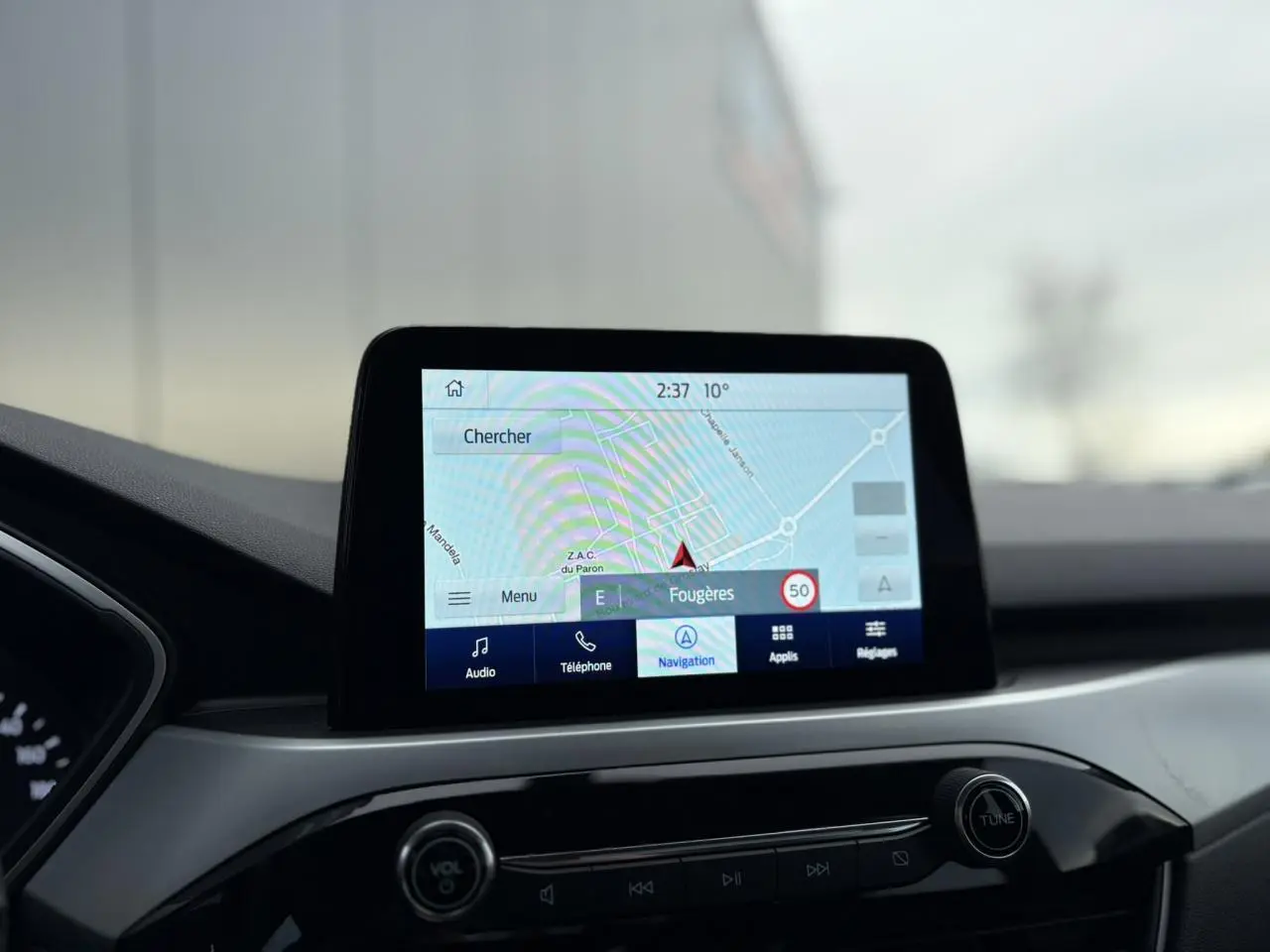 Écran tactile GPS du Ford Kuga 2024 affichant la navigation, vu de face dans l'habitacle noir.