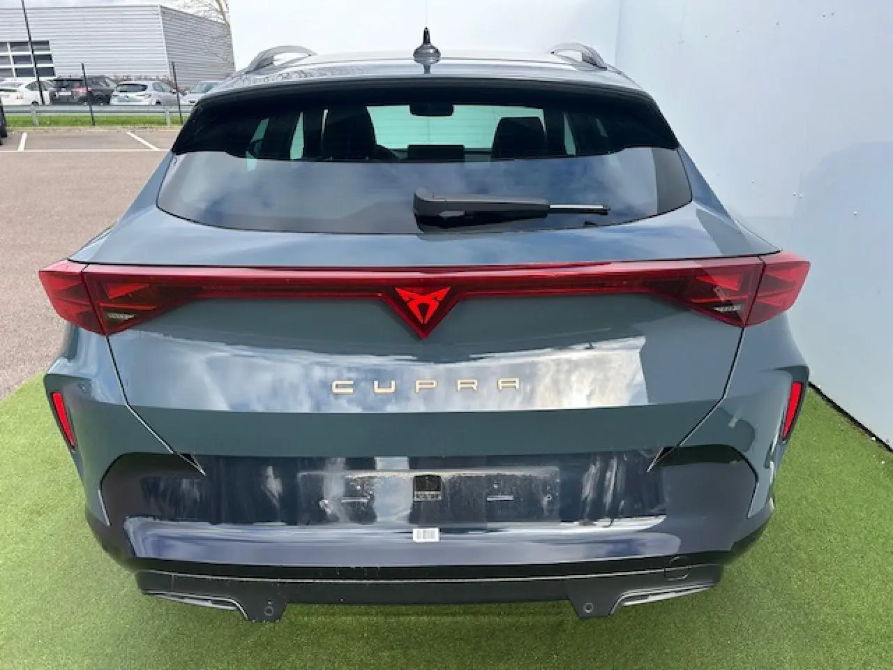 Vue arrière d'une CUPRA Formentor gris Fiord Metal avec bandeau lumineux rouge et logo CUPRA éclairé.