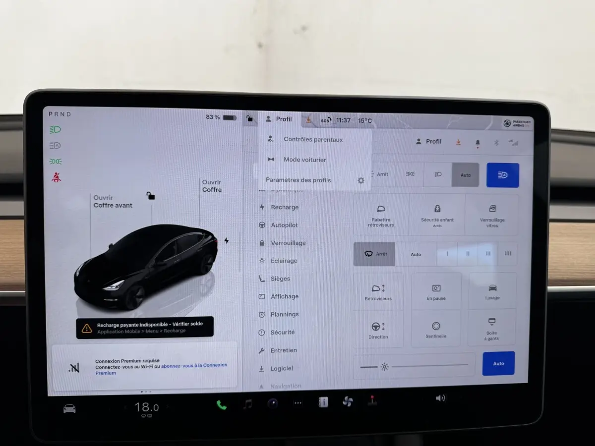 Écran tactile central affichant les réglages d’une Tesla Model 3 noire, vue de profil sur l’interface du véhicule.