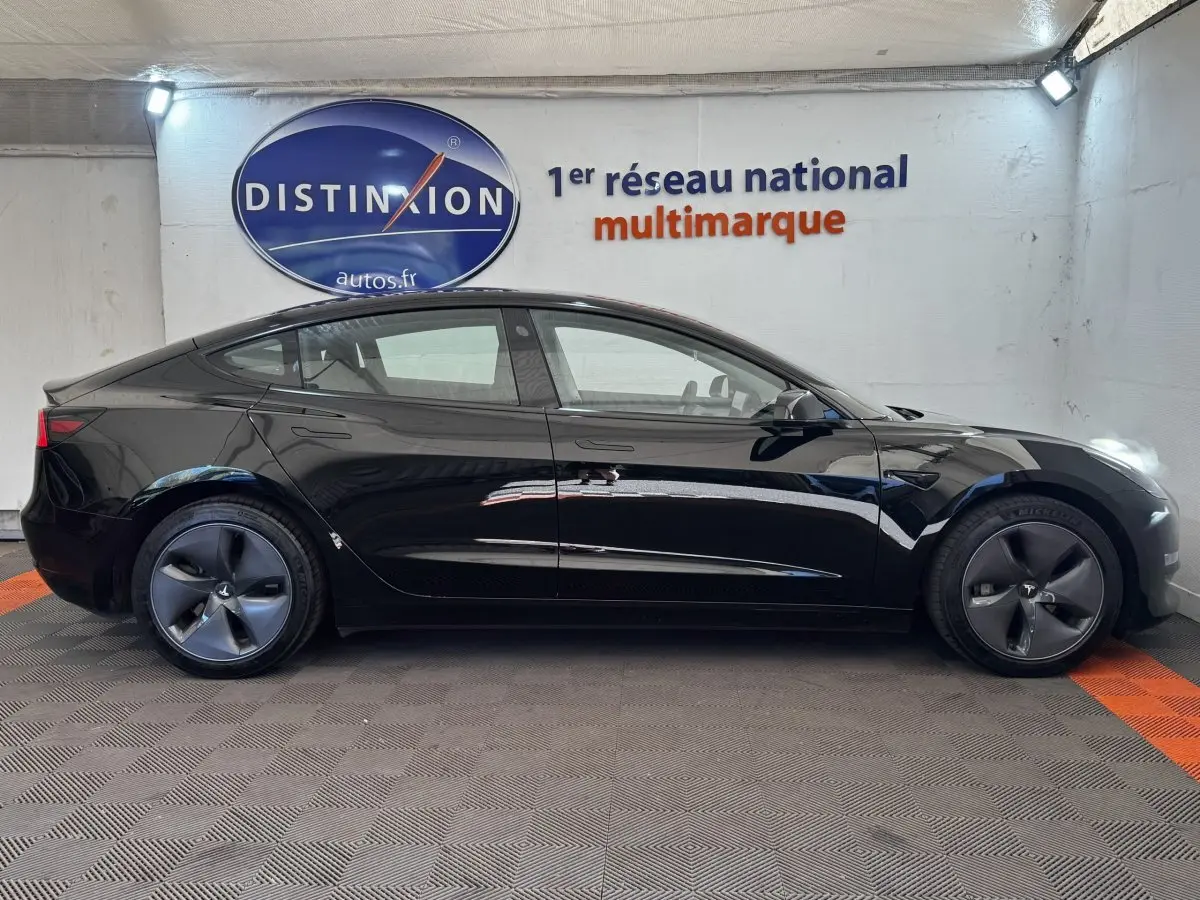 Profil latéral droit d'une Tesla Model 3 Grande Autonomie noire, avec jantes aérodynamiques et poignées affleurantes.