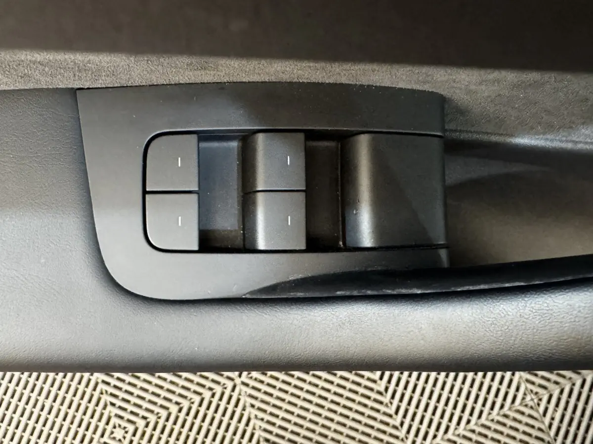 Détail des commandes de réglages mémorisables sur la portière intérieure d'une Tesla Model 3 noire 2023.
