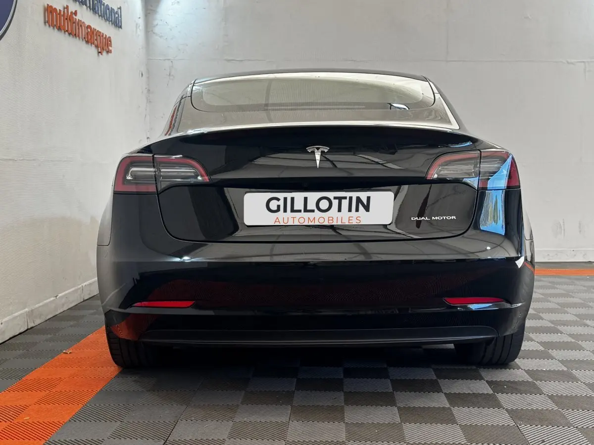 Vue arrière d'une Tesla Model 3 Grande Autonomie noire, avec feux LED et logo Tesla bien visibles.