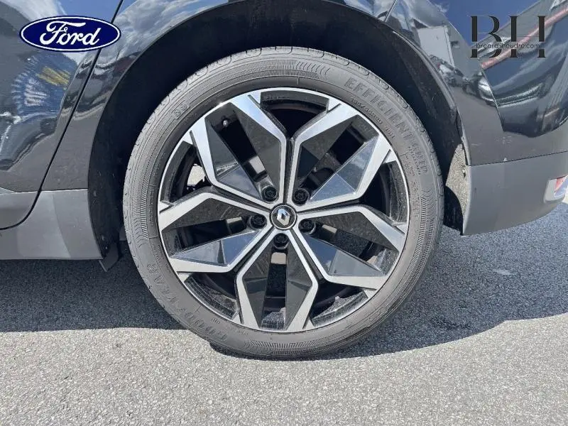 Gros plan sur la roue avant droite du Renault Grand Scenic noir étoilé avec jante alliage 20 pouces au design géométrique.