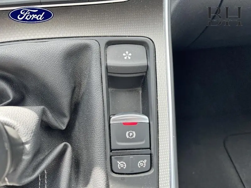 Gros plan sur la console centrale noire avec levier de vitesse manuel et boutons de frein à main électronique et régulateur de vitesse.