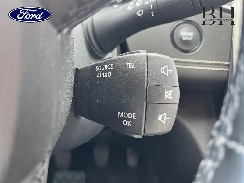 Gros plan sur les commandes audio au volant du Renault Grand Scenic noir étoilé, avec bouton start/stop en arrière-plan.