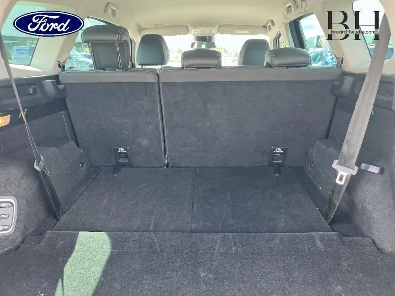 Vue arrière du coffre noir étoilé du Renault Grand Scenic 7 places avec banquette rabattue et ceinture de sécurité visible.