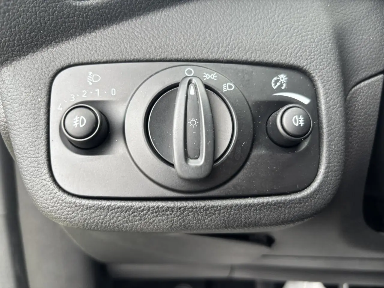 Gros plan sur le bouton de commande des phares et antibrouillards du tableau de bord d'une Ford C-MAX gris clair.