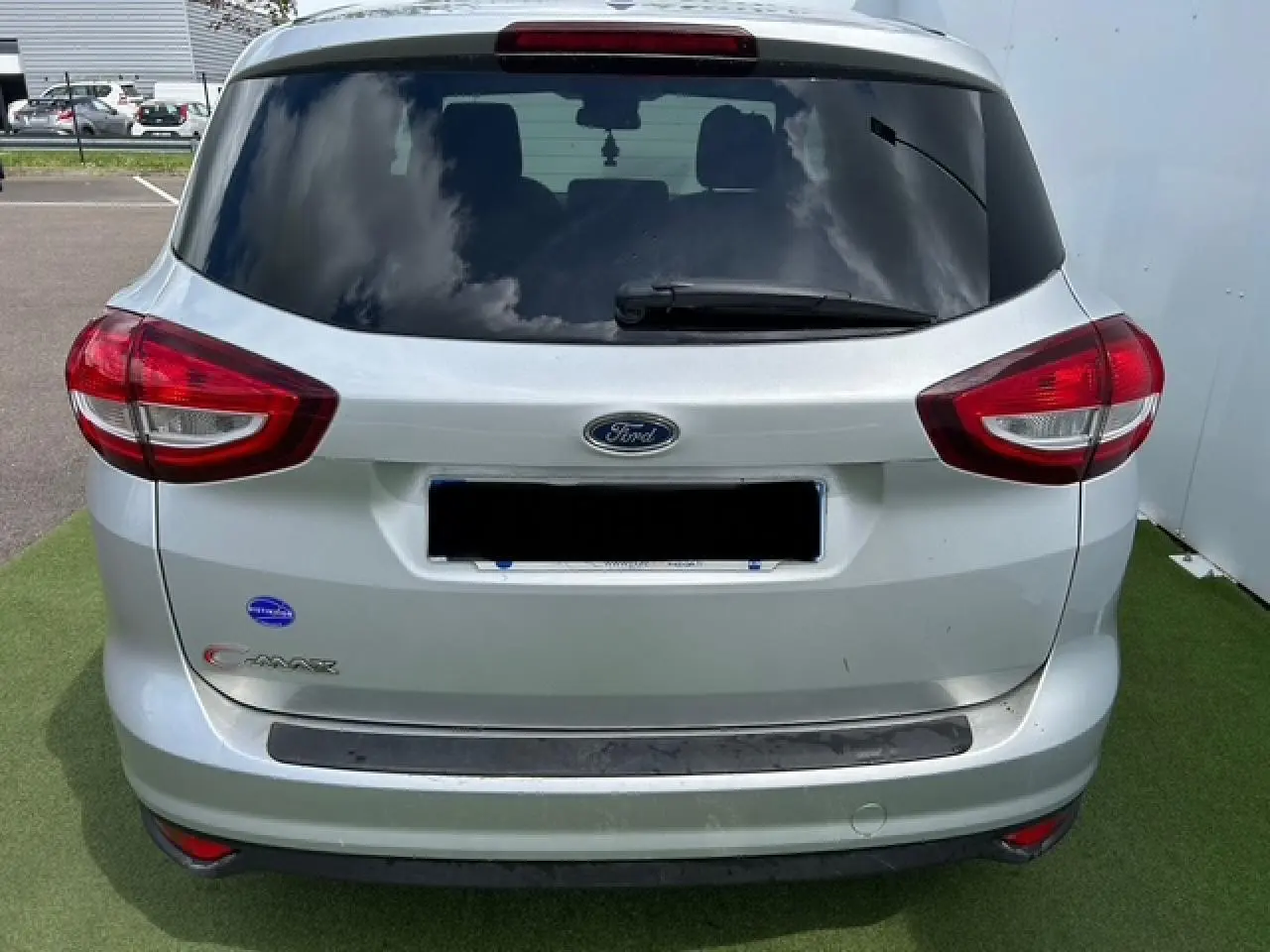 Vue arrière du Ford C-MAX gris clair métal avec vitres arrière surteintées et feux rouges distinctifs.