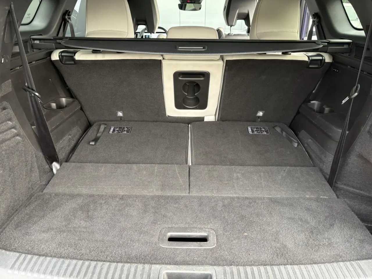 Coffre ouvert du Renault Espace VI 6 E-Tech bleu nuit, montrant les sièges arrière rabattus et la sellerie claire.