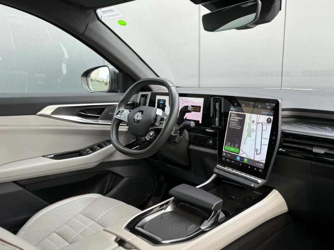 Vue intérieure côté conducteur du Renault Espace VI hybride, avec sellerie cuir gris sable clair et écran tactile vertical.