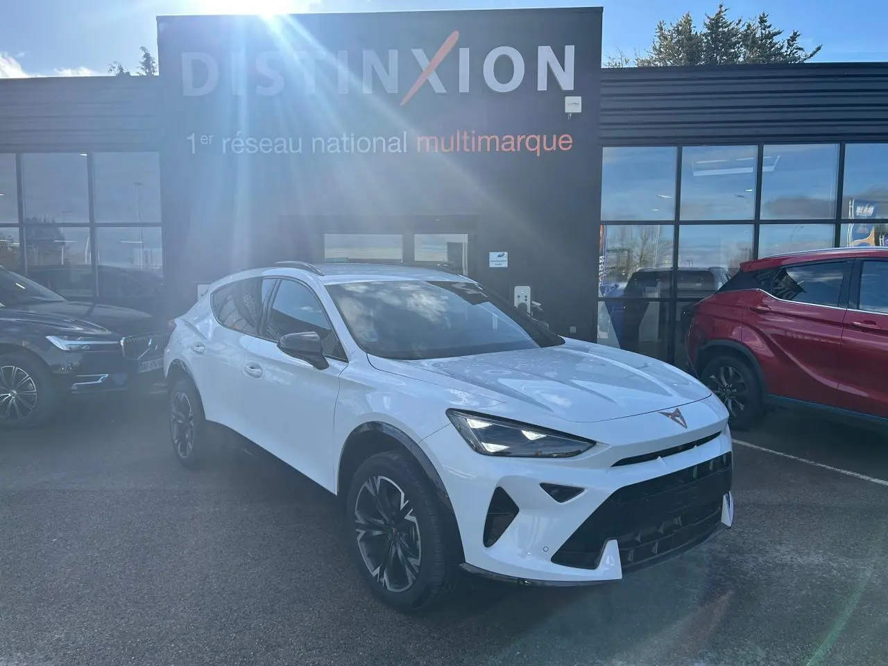 Vue 3/4 avant droite d'une CUPRA Formentor blanc neige avec jantes alliage 18'' et toits noir piano en arrière-plan showroom.