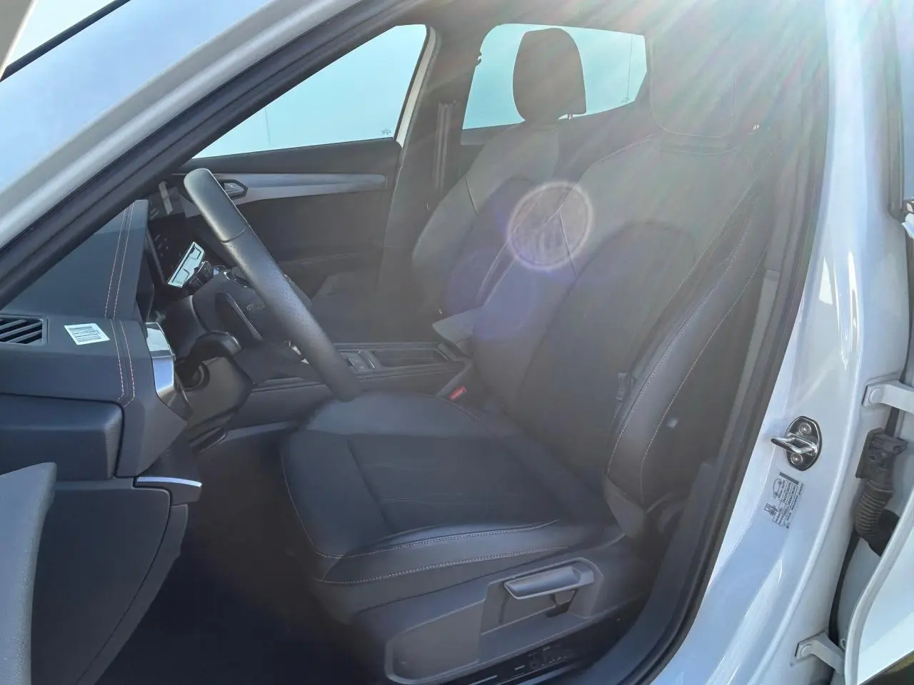 Vue intérieure côté conducteur du CUPRA Formentor blanc neige 2025, siège avant en tissu noir avec surpiqûres contrastantes.