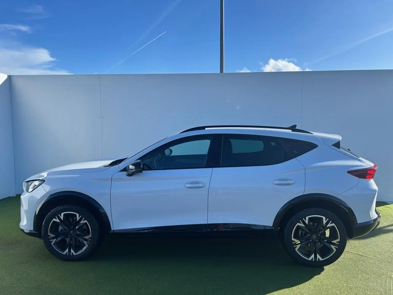 Vue de profil côté gauche du CUPRA Formentor blanc neige 2025 avec jantes alliage noires et éléments noirs contrastants.