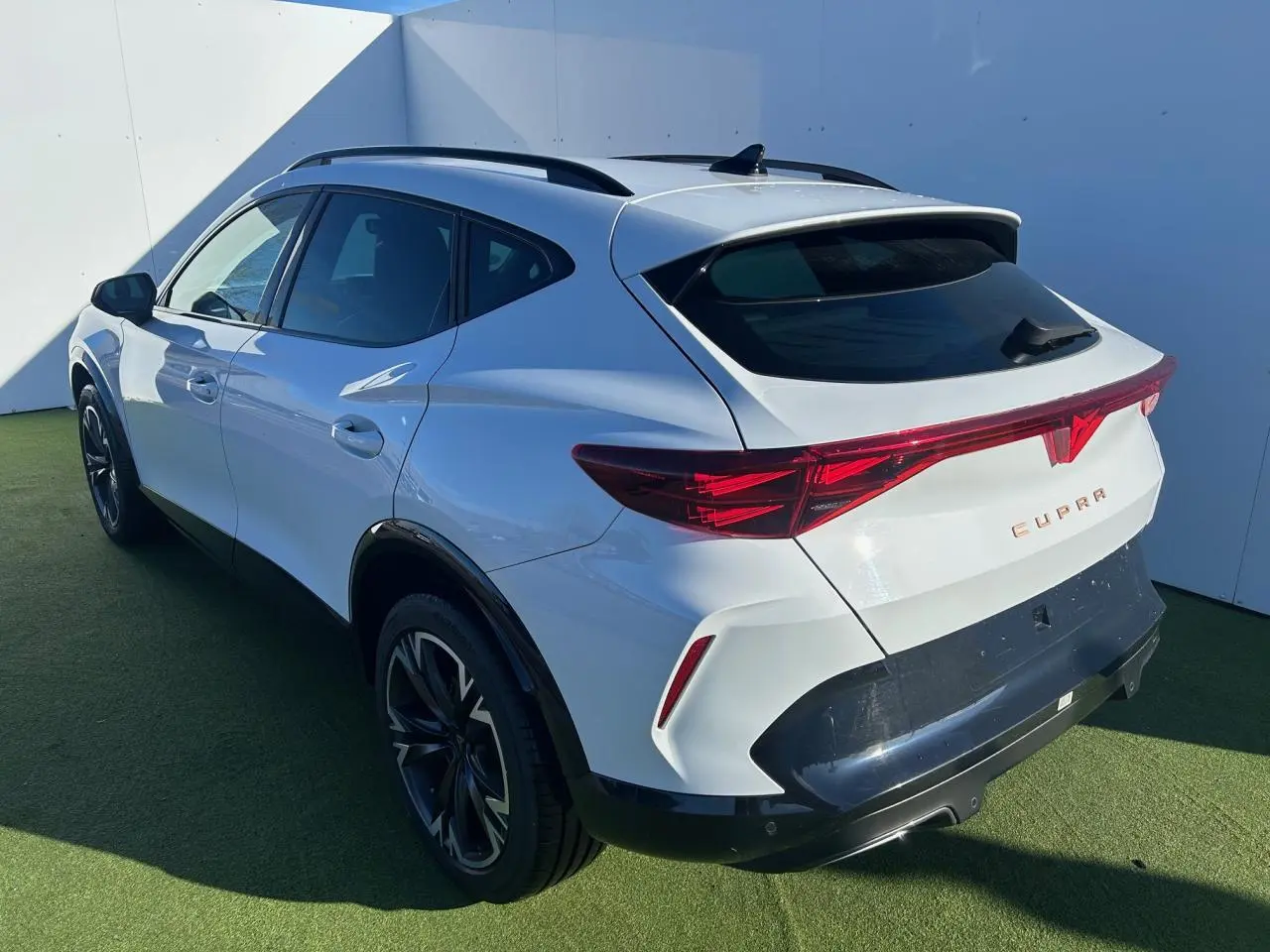 Vue 3/4 arrière droite du CUPRA Formentor blanc neige avec bandeau lumineux arrière et jantes alliage noires.