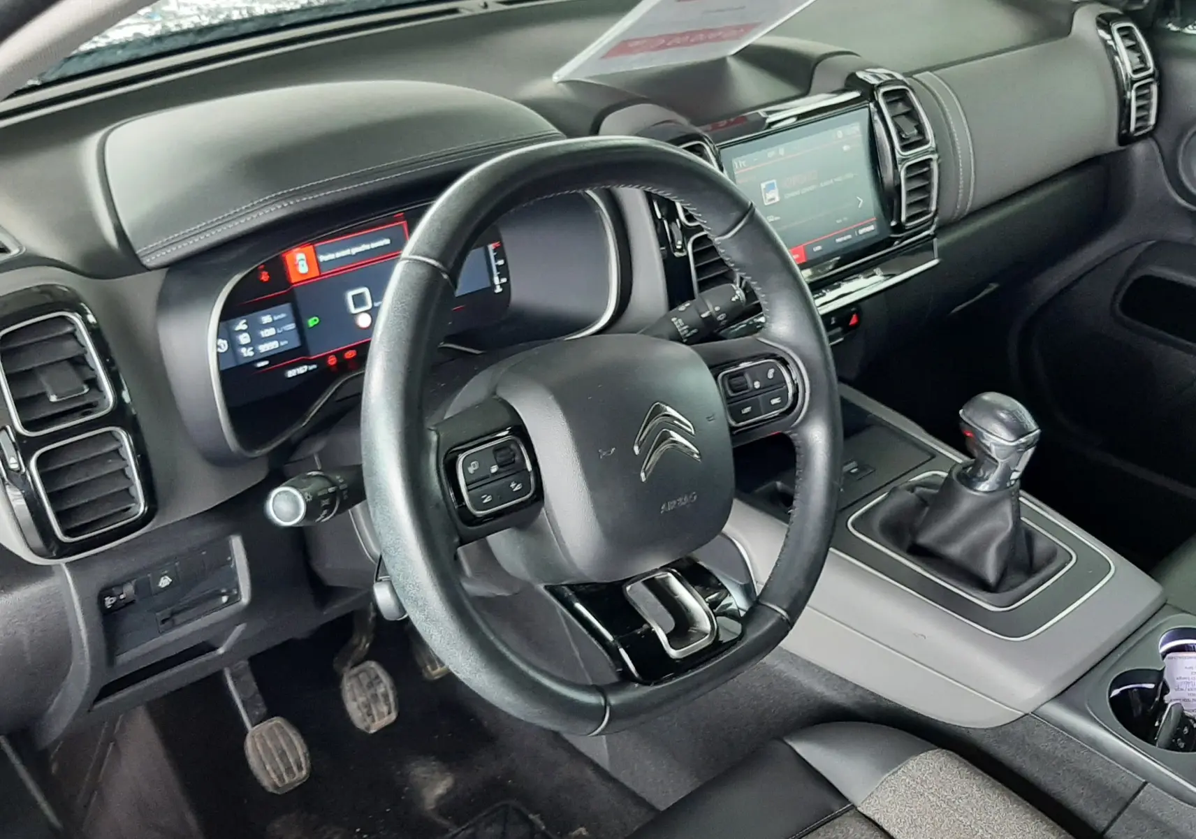 Vue intérieure du poste de conduite du Citroën C5 Aircross 1.2 PureTech 2021, volant cuir, boîte manuelle et écran tactile.