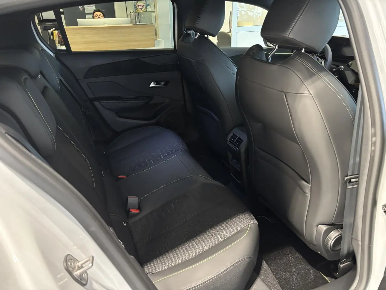 Vue intérieure arrière côté droit de la Peugeot 308 blanche avec sellerie noire et surpiqûres vert Adamite.