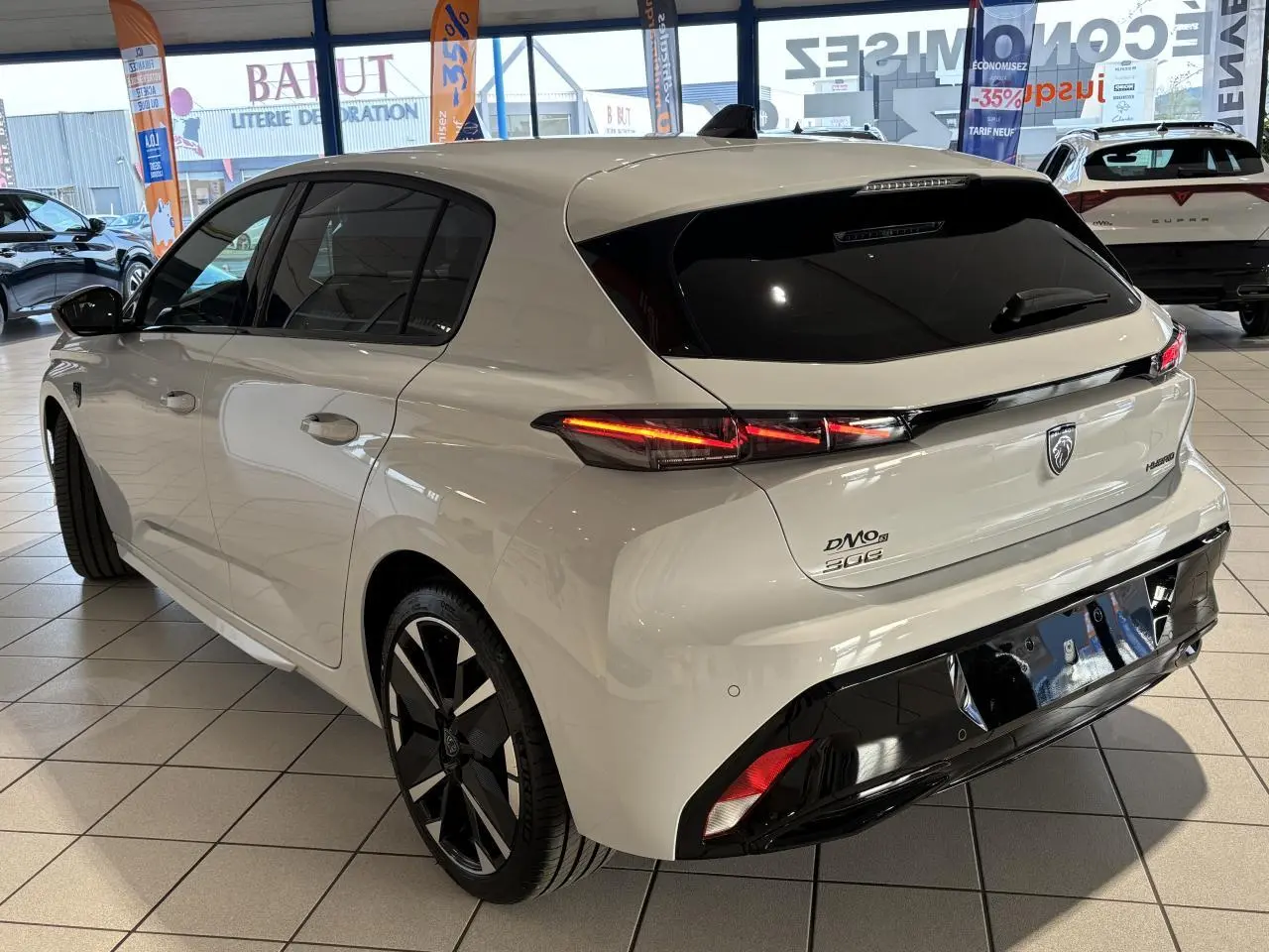 Vue 3/4 arrière droit d'une Peugeot 308 blanche Okenite avec feux arrière LED 3 griffes et jantes alliage bi-tons.