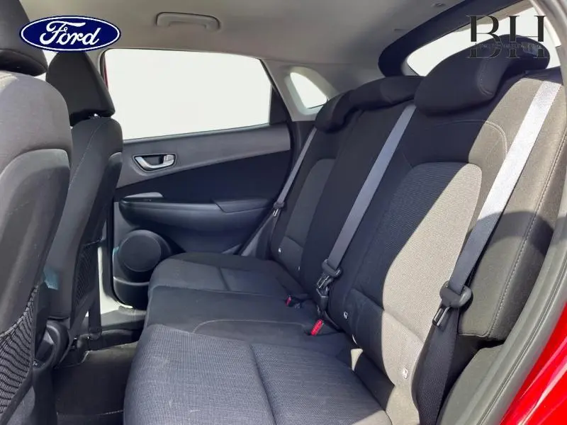 Vue intérieure côté droit des sièges arrière noirs d'une Hyundai Kona Pulse Red Métal, avec ceintures de sécurité visibles.