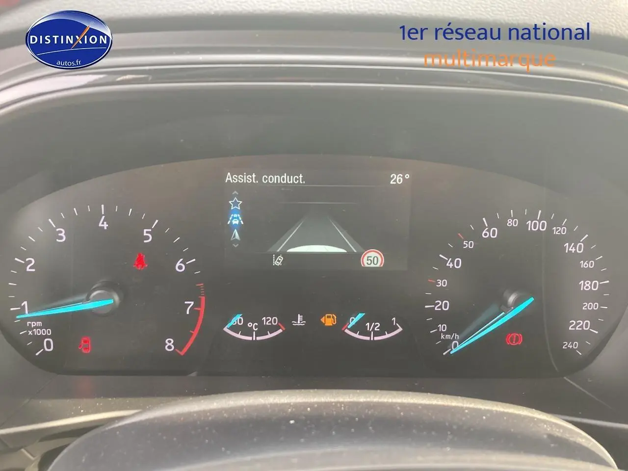 Vue rapprochée du tableau de bord numérique de la Ford Focus gris, affichant les compteurs et l'assistance à la conduite.