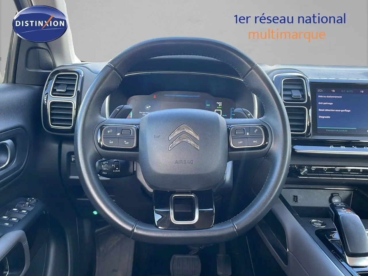 Vue rapprochée du volant noir et du tableau de bord digital du Citroën C5 Aircross blanc nacré hybride 2021.