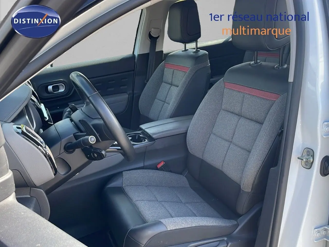 Vue intérieure côté conducteur du Citroën C5 Aircross blanc nacré, sièges gris tissu et cuir noir avec bande rouge.