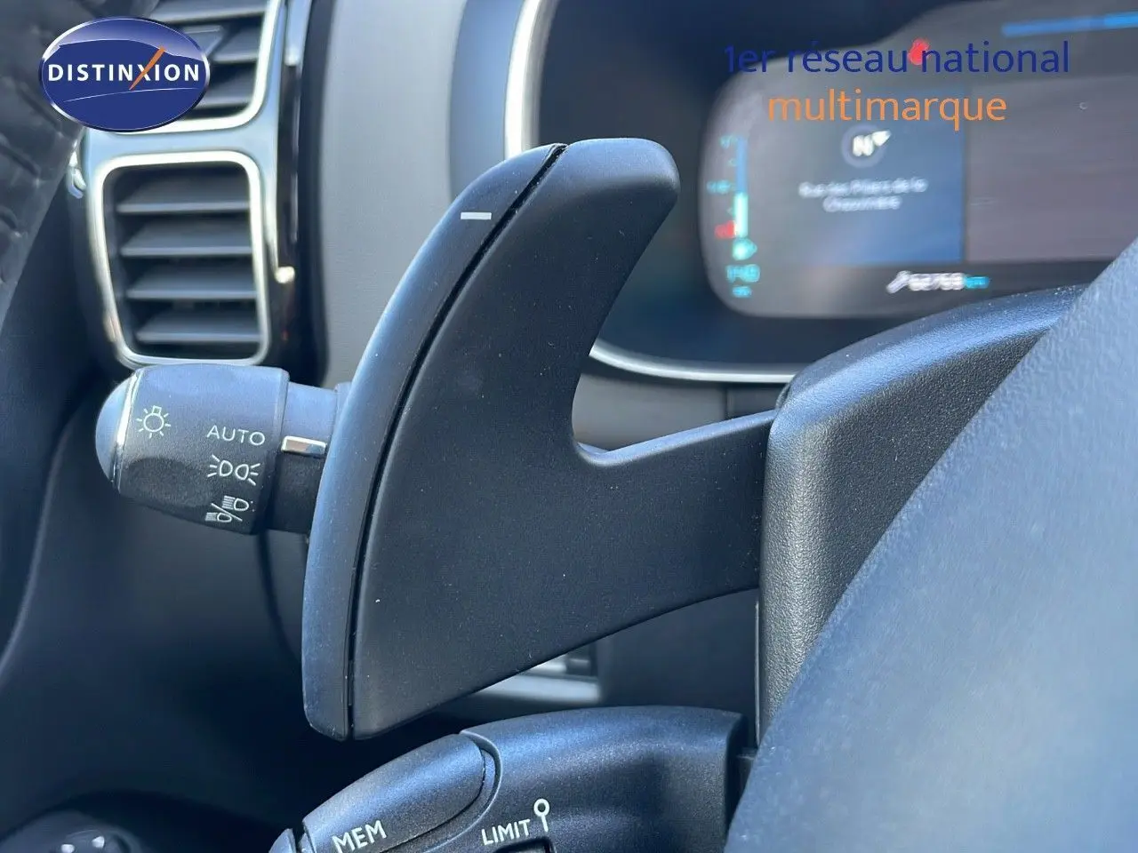 Gros plan sur la palette de changement de vitesses au volant d'un Citroën C5 Aircross blanc nacré hybride, tableau de bord en arrière-plan.