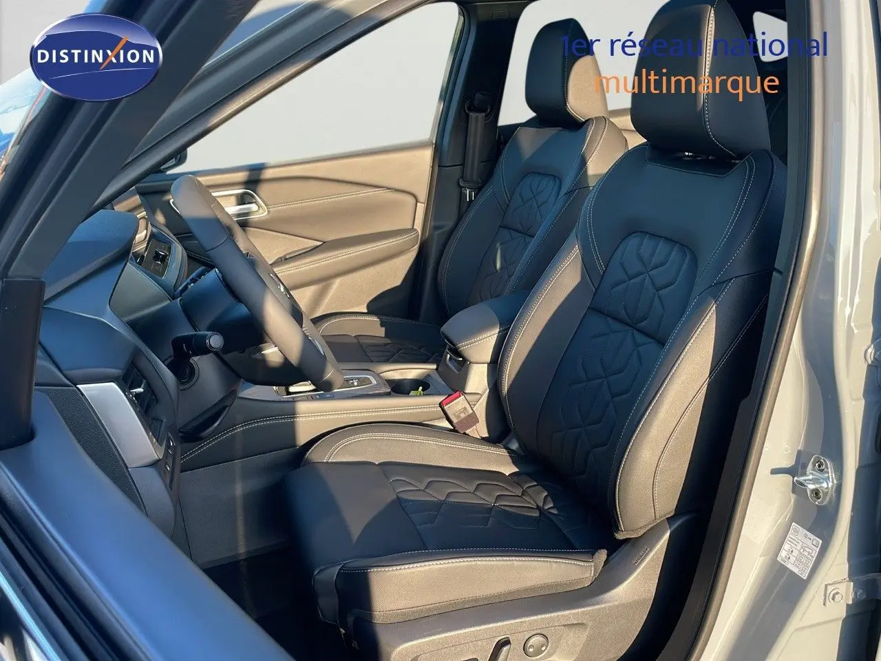 Intérieur du Nissan Qashqai 2025 gris céramique, vue côté conducteur sur sièges cuir noir avec surpiqûres blanches.