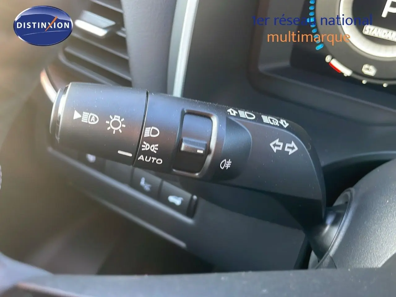 Gros plan sur la commande des phares et clignotants du Nissan Qashqai 2025, intérieur noir avec tableau de bord partiel visible.