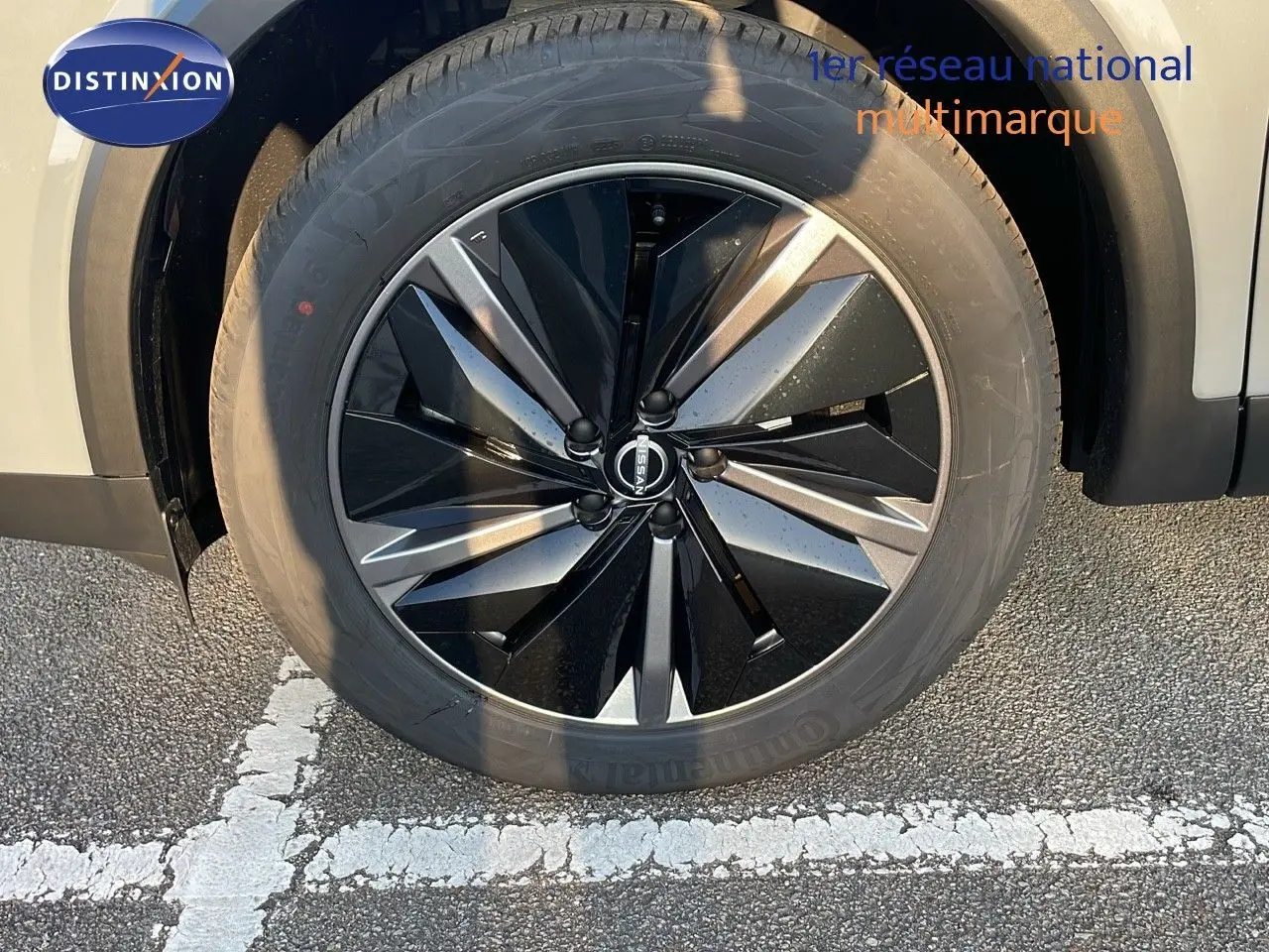 Gros plan sur la jante noire et grise du Nissan Qashqai 2025 gris céramique métal, avec logo Nissan visible au centre.