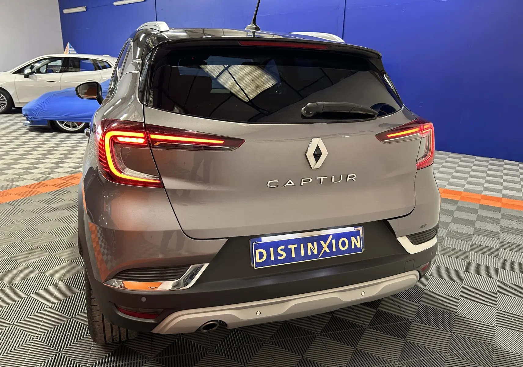 Vue arrière d’un Renault Captur gris 2020 avec feux LED allumés dans un showroom au sol damier.