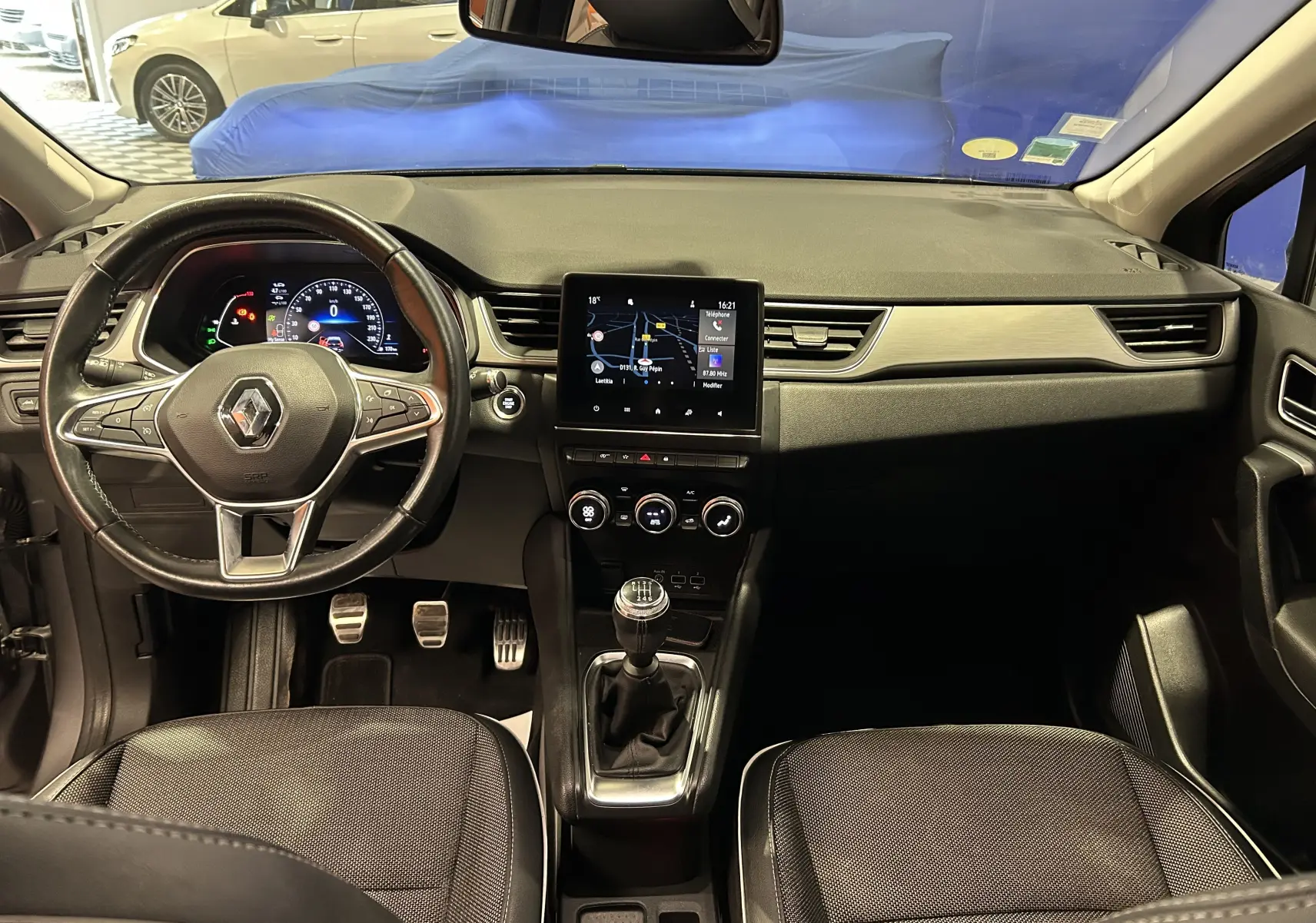 Vue intérieure avant du Renault Captur gris 2020, avec volant cuir, tableau de bord numérique et écran tactile GPS central.
