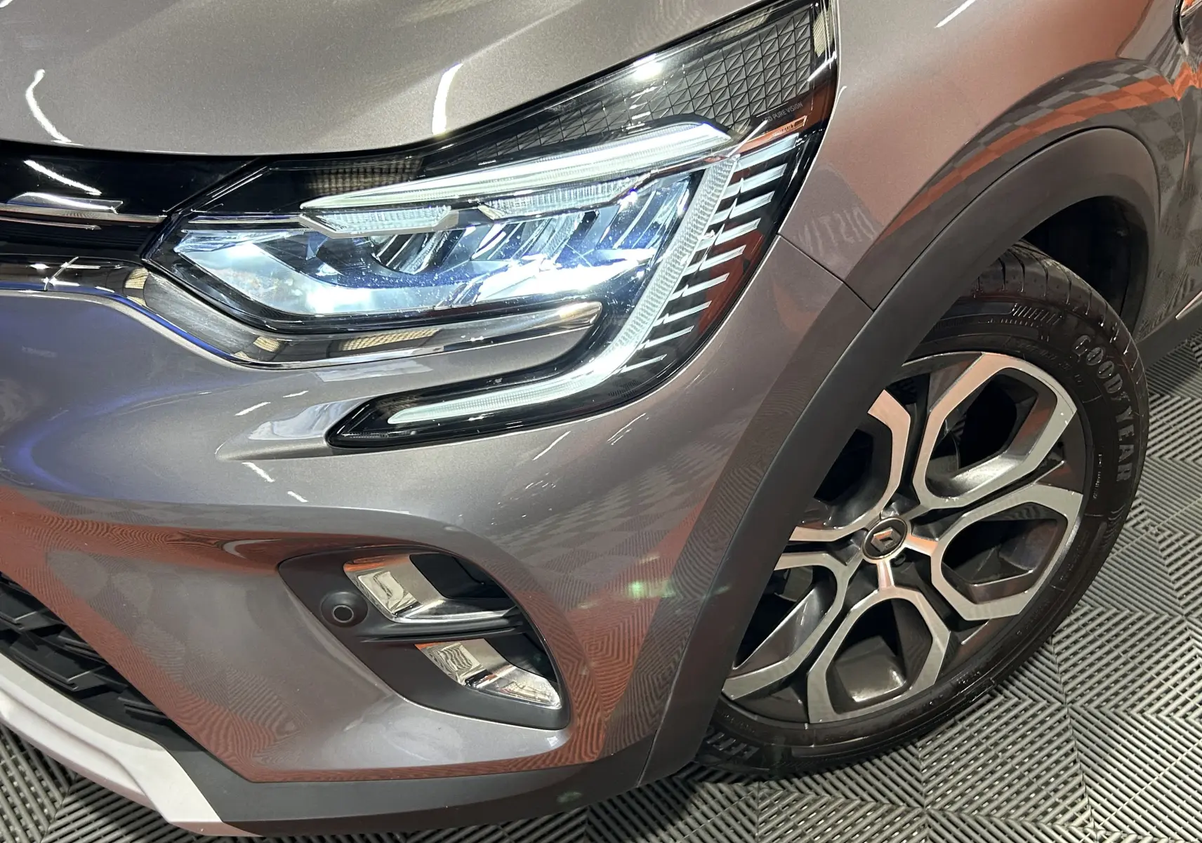 Gros plan sur l'avant droit gris du Renault Captur 2020, mettant en valeur le phare LED et la jante alliage distinctive.