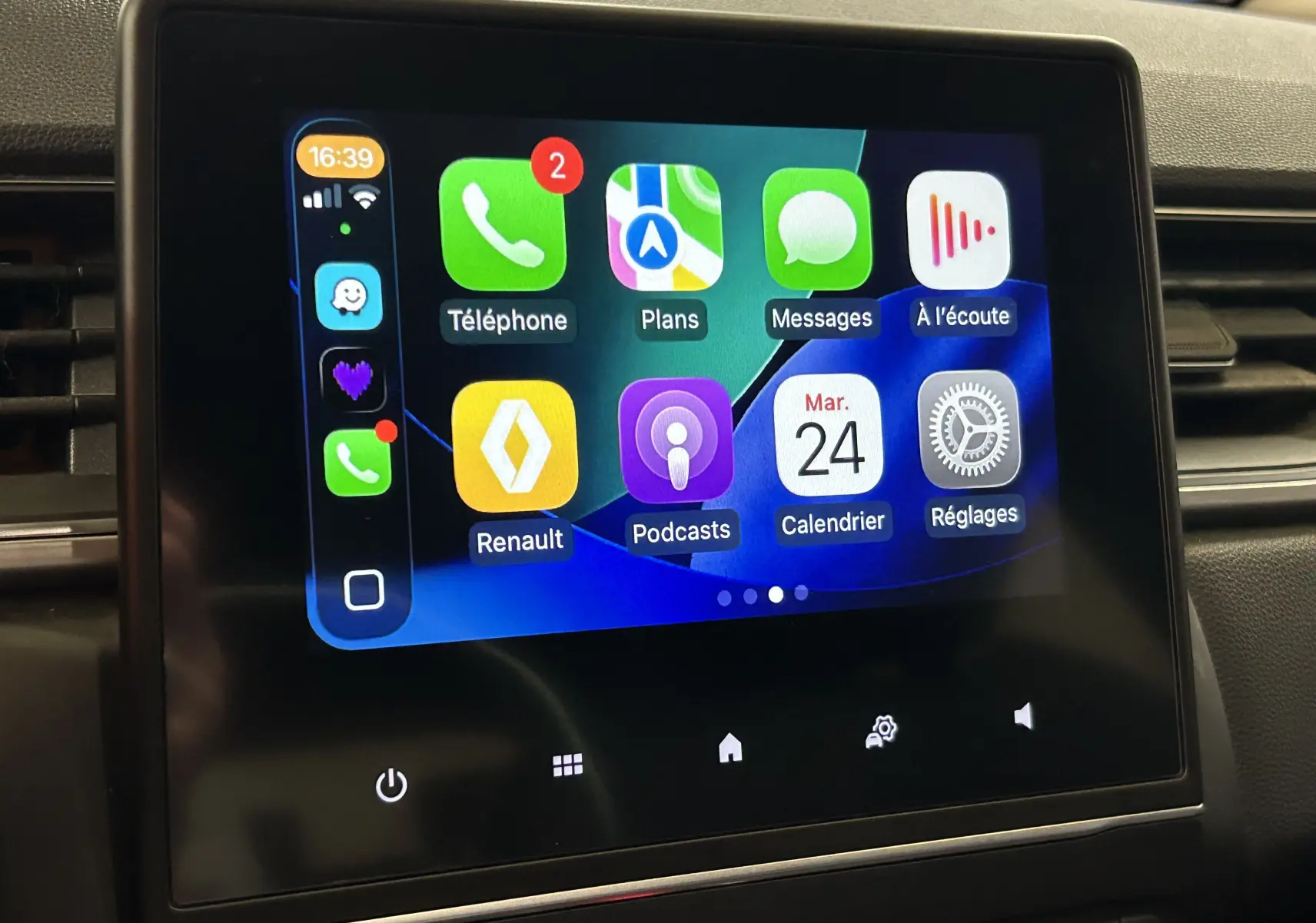 Écran tactile central affichant l'interface Apple CarPlay dans l'habitacle d'un Renault Captur gris.